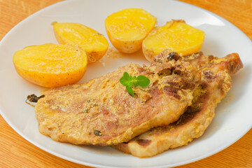 Pork meat with mustard and potatoes on plate