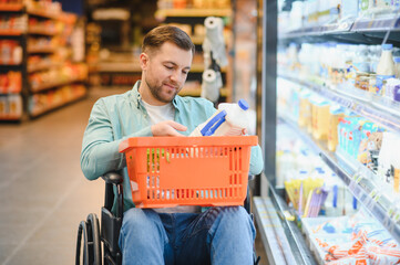 Customer in wheelchair choosing milk in supermarket refrigerator section