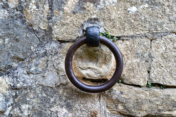 Close up of an old rusty iron ring mounted on a stone wall