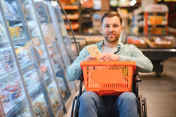 Customer using wheelchair buying groceries in supermarket