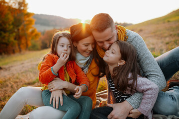 Parents with young children sitting outdoors in autumn light.