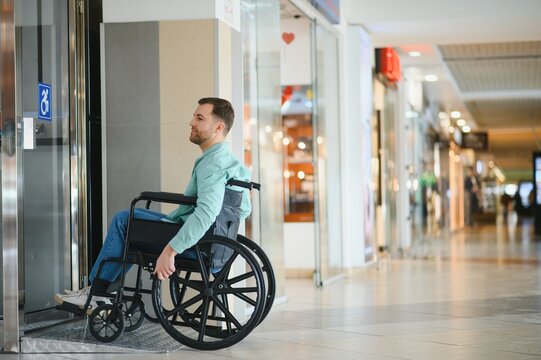 Man in wheelchair exiting elevator in shopping mall