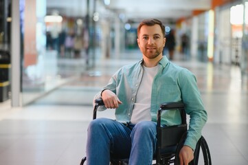 Smiling man sitting in wheelchair moving through shopping mall corridor