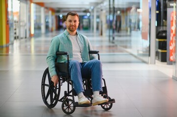 Smiling man using wheelchair enjoying shopping in mall