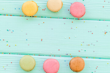 sweet dessert pattern with macarons on mint green wooden background flat lay mockup