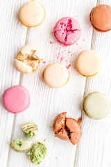 Brignt macarons for sweet break on white wooden background top view pattern