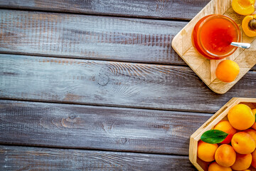 Healthy breakfast. Apricot jam in jar near fresh fruits on dark wooden background top view frame space for text