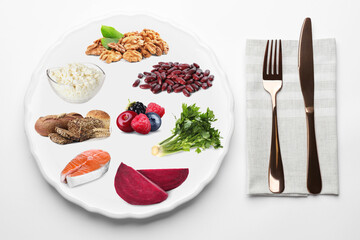 Plate with collection of different foods and cutlery on white background, top view. Healthy eating