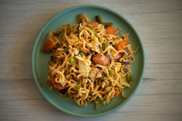 Smoky Asian egg noodles, chicken, prawn, shrimp and vegetables on a gray background.