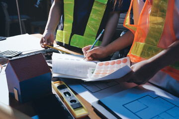 Closeup of team of industrial engineers meeting analyze machinery blueprints consult project on table in manufacturing factory. Working in manufacturing plant or production plant.