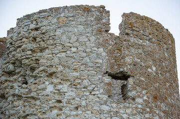 A weathered stone tower wall with a narrow opening stands as a silent relic of ancient...