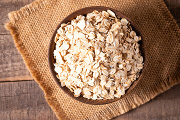 Raw oats in a wooden bowl on a wooden background. Organic food concept. 