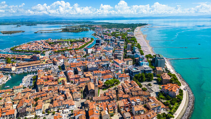 Aerial view of Grado, a picturesque seaside town in Friuli Venezia Giulia, Italy. The photo shows the historic old town with red-tiled roofs, charming harbor, long sandy beaches, blue water © Viktor