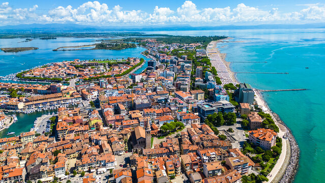 Aerial view of Grado, a picturesque seaside town in Friuli Venezia Giulia, Italy. The photo shows the historic old town with red-tiled roofs, charming harbor, long sandy beaches, blue water