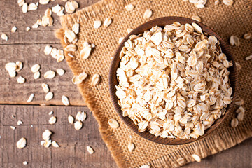 Raw oats in a wooden bowl on a wooden background. Organic food concept. 