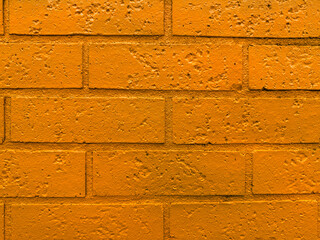Close-up of an orange-painted brick wall with visible texture and rough surface, ideal for use as a...