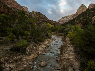 Obraz premium View over the Virgin River, flanked by the mountains forming the edge of Zion Canyon in the soft blue light of twilight, in Zion National Park, Utah.