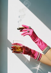 Hands in Pink Gloves Holding a Cigar and Whiskey Glass