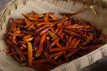 Pile of dried red chili peppers in a traditional bamboo basket used for cooking and spice preparation