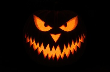 Fototapeta premium Glowing carved jack-o'-lantern with menacing expression for halloween night