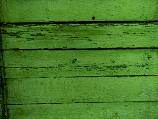 Closeup of weathered green wooden planks with peeling paint and rough texture