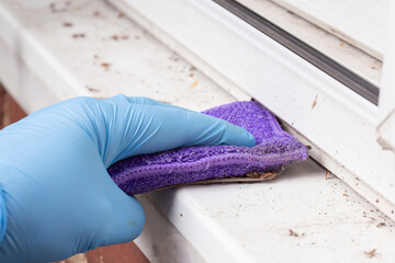 Person cleaning the cill on a PVC sliding patio door with a pad. background. Household chore concept