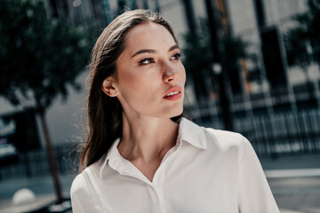 Confident professional woman outdoors in an urban setting with modern buildings and stylish attire