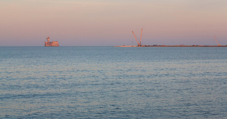 Dagestan, Russia - 25 October 2020: Fortress in the Caspian Sea and port in the background at sunset with the pink sky and Caspian Sea