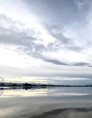 Obraz premium A tranquil landscape showcases a calm body of water reflecting a soft, overcast sky.