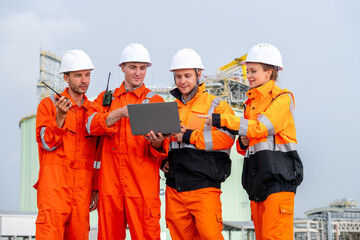 Team of construction workers collaborating at a construction site while reviewing plans on a laptop