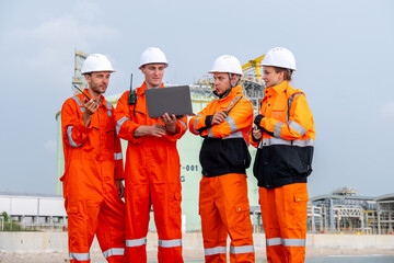 Construction workers collaborate on project planning at an industrial site during clear weather