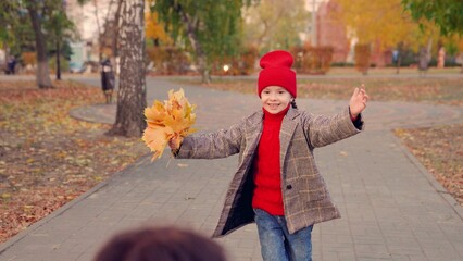 Child daughter runs to mom, hugs her in autumn Park. Happy family. Carefree childhood, joyful...