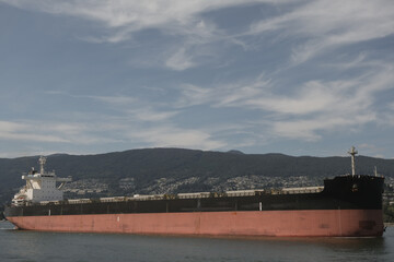 Massive cargo container ship arriving in Vancouver port, BC British Columbia in Canada on sunny day...