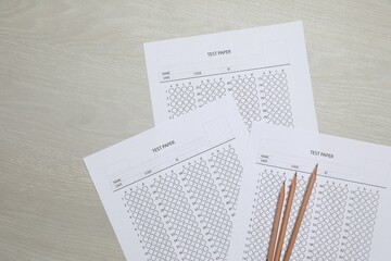 Answer sheets and pencils on wooden table, flat lay. Student passing exam