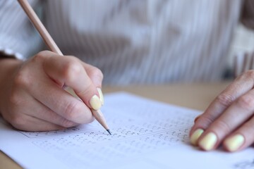 Student filling out multiple choice test at table, closeup. Passing exam