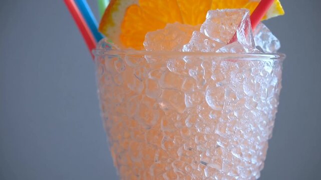chilled citrus-based or orange-flavored frozen beverage served in tall glass with straw, consisting of sweet fruit ice shavings for non-alcoholic summer refreshment