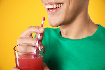 Man with juice and drinking straw on orange background, closeup
