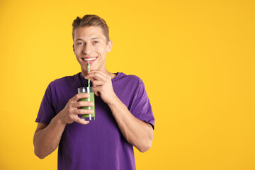 Man drinking juice through straw on orange background, space for text
