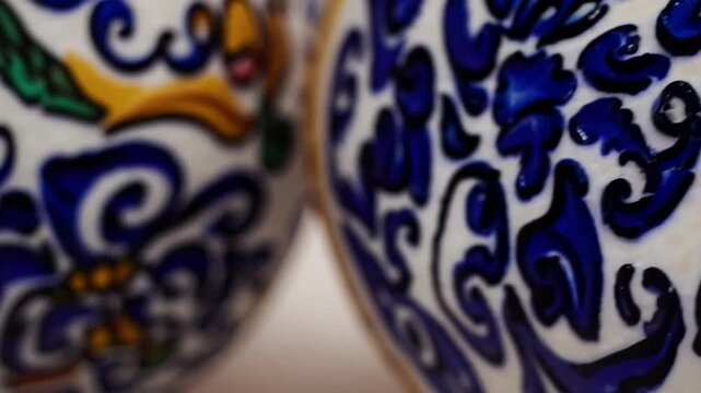 Intricately detailed, hand-painted Mexican ceramic pottery, showcasing Talavera designs with stenciled glaze patterns suggesting soft focus and blurred edges