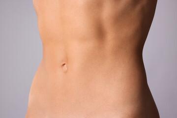 Woman with flat belly on grey background, closeup