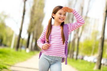 Smiling girl enjoying a sunny day outdoors while looking into the distance on a city street