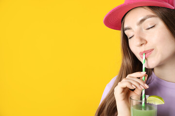 Woman drinking refreshing drink through straw on orange background, space for text