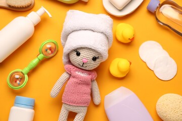 Baby bath accessories, care products and toys on orange background, flat lay