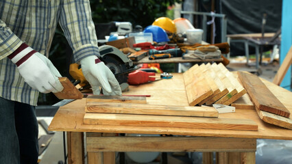 Carpenter measuring wooden plank with ruler on workbench surrounded by tools and safety equipment