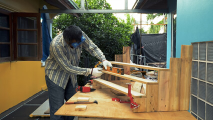 Worker in gloves using spirit level to measure alignment of wooden staircase-like structure outdoors