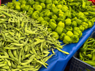 Green peas in pods spread across market stall surface. Agriculture, farming, and seasonal legume...