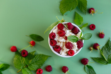 Natural cottage cheese with red raspberries and greens close-up