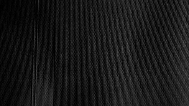 Black textured rough paper with glued parts and parallel lines. Abstract dark background. Rotation