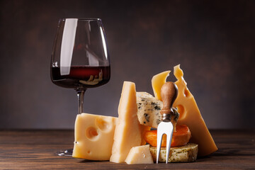Assorted cheeses paired with glass of wine on a rustic table
