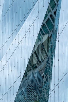 Modern skyscraper detail with reflective glass panels angled against sky, architectural geometry showing strength, vertical rhythm and progressive urban identity in contemporary design